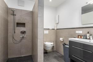 a bathroom with a shower and a toilet and a sink at Vivamosel: Appartement mit Mosel & Burgblick - Balkon - Parken - Aufzug - Fahrradraum in Cochem