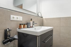 La salle de bains est pourvue d'un lavabo blanc. dans l'établissement Vivamosel: Appartement mit Mosel & Burgblick - Balkon - Parken - Aufzug - Fahrradraum, à Cochem