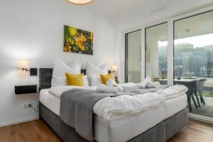 Un dormitorio con una cama grande con almohadas amarillas y blancas en Vivamosel: Appartement mit Mosel & Burgblick - Balkon - Parken - Aufzug - Fahrradraum, en Cochem