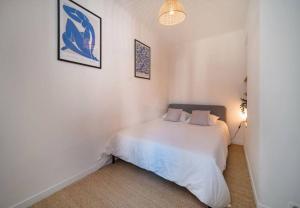 um quarto com uma cama branca e duas fotografias na parede em Maison au cœur de l’Estaque em Marselha