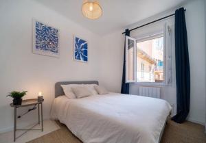 a bedroom with a white bed and a window at Maison au cœur de l’Estaque in Marseille