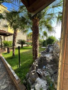 un cortile con palme e un muro di pietra di Mary's House a SantʼEufemia Lamezia