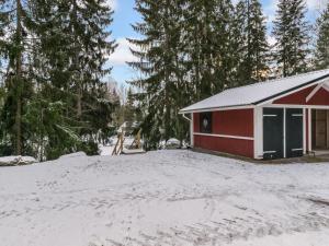 une grange rouge dans la neige avec des arbres dans l'établissement Holiday Home Mäkimökki by Interhome, à Palikainen