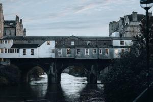 un tren cruzando un puente sobre un río con edificios en Stunning Boutique Flat in Central Location - Beatrice en Bath