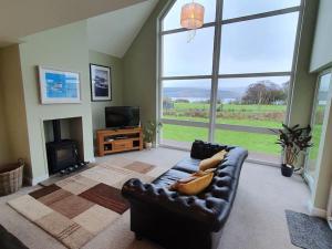 a living room with a leather couch and a fireplace at Otter House in Arle