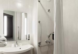 La salle de bains blanche est pourvue d'une douche et d'un lavabo. dans l'établissement B&B HOTEL Noisy-le-Grand, à Noisy-le-Grand
