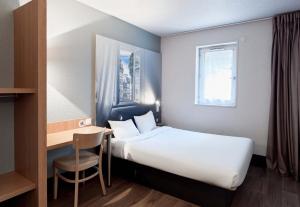 ノワジー・ル・グランにあるB&B HOTEL Noisy-le-Grandのベッド、デスク、窓が備わるホテルルームです。