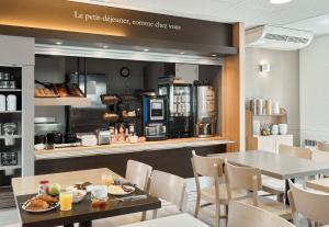 ノワジー・ル・グランにあるB&B HOTEL Noisy-le-Grandのテーブルと椅子のあるレストラン、コーヒーショップ