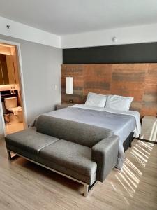 een slaapkamer met een groot bed en een bank bij Flat particular incrível dentro do hotel M Ibirapuera em Moema in Sao Paulo