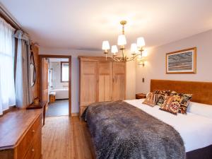 a bedroom with a large bed and a chandelier at Chalet Chalet Tetras by Interhome in Chesières