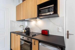 a kitchen with a black counter top with a microwave at Superb apartment- 4P- Montorgueil Nazareth in Paris