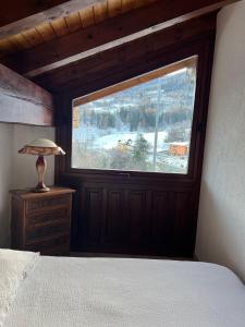 Dormitorio con ventana, cama y lámpara en Casa Rina, en Gignod