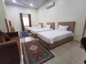 two beds in a room with a couch and a room with at Sohar Hotel - فندق صحار in Sohar