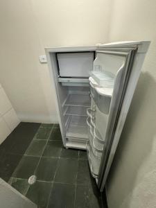 an empty refrigerator with its door open in a room at Quarto Central in Guararema