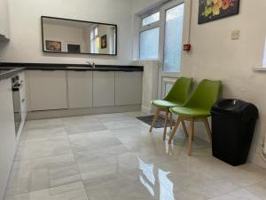 a kitchen with green chairs and a sink and a mirror at Elm, Large 5 Bedrooms, Sleeps 10 With Parking in Birmingham