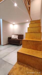 sala de estar con escaleras y sofá en Loft Rústico - Curitiba, en Curitiba