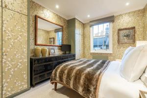 sypialnia z łóżkiem i lustrem w obiekcie JOIVY Elegant 1 bed flat in Chelsea w Londynie