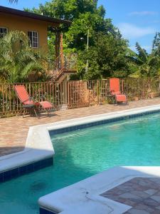 a swimming pool with two chairs and a house at Montego Bay, Ironshore Luxury Studio in Montego Bay