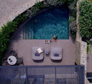 una piscina con sedie e una persona seduta accanto ad essa di Noima Boutique Hotel Mykonos ad Agios Ioannis