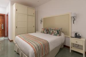 a bedroom with a bed and a night stand with a phone at Hotel Emblemático Holiday Time in Santa Cruz de la Palma