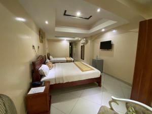 um quarto de hotel com uma cama e uma televisão em La Grande Hotel em Kampala