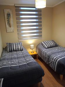 two beds in a bedroom with a window and a lamp at San Pedro de la Paz by Luxury Apartment Chile in San Pedro de la Paz