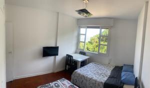 um quarto com uma cama, uma escrivaninha e uma janela em Vista Maravilhosa em São Vicente