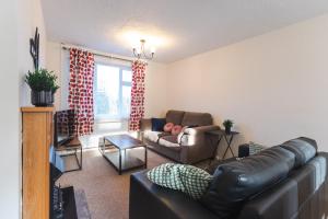 a living room with a leather couch and a chair at April Disc - Long Stay - Contractors in Swindon