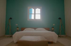 1 dormitorio con 1 cama con 2 luces y una ventana en Wostel Djerba, en Erriadh