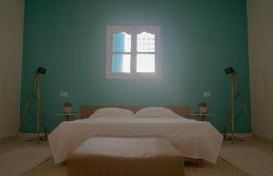 a bedroom with a bed with two lights and a window at Wostel Djerba in Erriadh