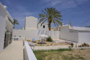a white building with a palm tree in the background at Wostel Djerba in Erriadh