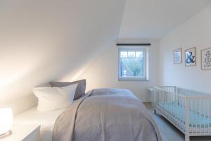 a white bedroom with a bed and a crib at Kleine Flucht in Tating