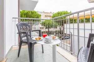 una mesa y sillas en un balcón con una taza de café en Hotel Luana, en Riccione