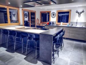 a kitchen with a large island with bar stools at Chalet spacieux & spa in Landry