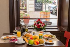 ブダペストにあるThree Corners Hotel Artの食べ物の皿と窓のある朝食テーブル