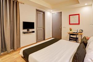 a hotel room with a bed and a television at Super OYO Townhouse 141 Sector 14 Old Gurgaon in Gurgaon