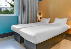 a large white bed in a room with a window at B&B HOTEL Reims Centre Gare in Reims