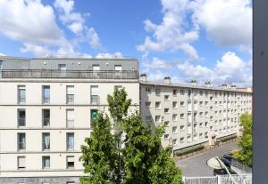 um prédio de apartamentos com uma árvore em frente em B&B HOTEL Reims Centre Gare em Reims