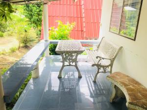 un patio con 2 bancos y una mesa en un porche en LungYod guesthouse, en Ban Tha Ling Lom