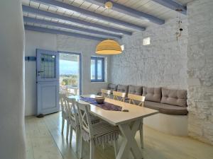 a dining room and living room with a table and chairs at Cycladic Villa, Blue Stories in Santa Marina