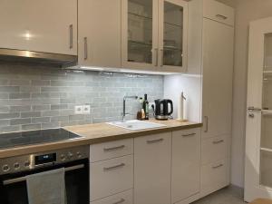 a kitchen with white cabinets and a sink at moderne 2-Zimmer-Wohnung mit Terrasse in Tönnhausen