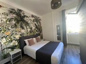 a bedroom with a bed with a tropical wallpaper at H&ocirc;tel Parc Mazon-Biarritz in Biarritz