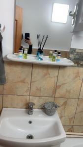 a sink in a bathroom with a person taking a picture at Nova Montan Azuga in Azuga +11 photos
