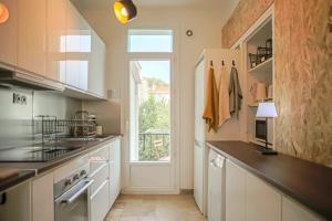 a kitchen with white cabinets and a window at Cocon à Toulon proche de l'Arsenal. 10mn à pied du centre in Toulon