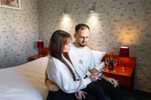 mężczyzna i kobieta siedzący na łóżku patrzący na komórkę w obiekcie Victory Home Rooms w Warszawie