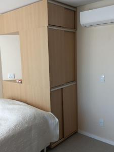 een slaapkamer met een bed en een houten kast bij Apartamento 2 quartos 200 m da praia in Lauro de Freitas