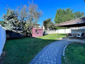 a backyard with a brick walkway and a pink shed at Modern and spacious 4 B/R + 2 bath house in Westbury