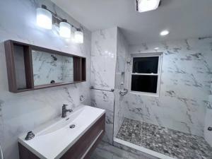 a white bathroom with a sink and a window at Modern and spacious 4 B/R + 2 bath house in Westbury