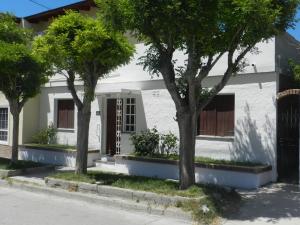 uma casa branca com árvores em frente em Lo de Lili em Puerto Madryn