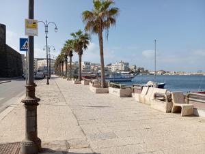 a sidewalk with benches and palm trees next to the water at Da Gianni in Pantelleria